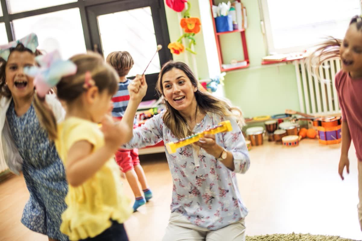 Preschool teacher playing music with young children in a classroom